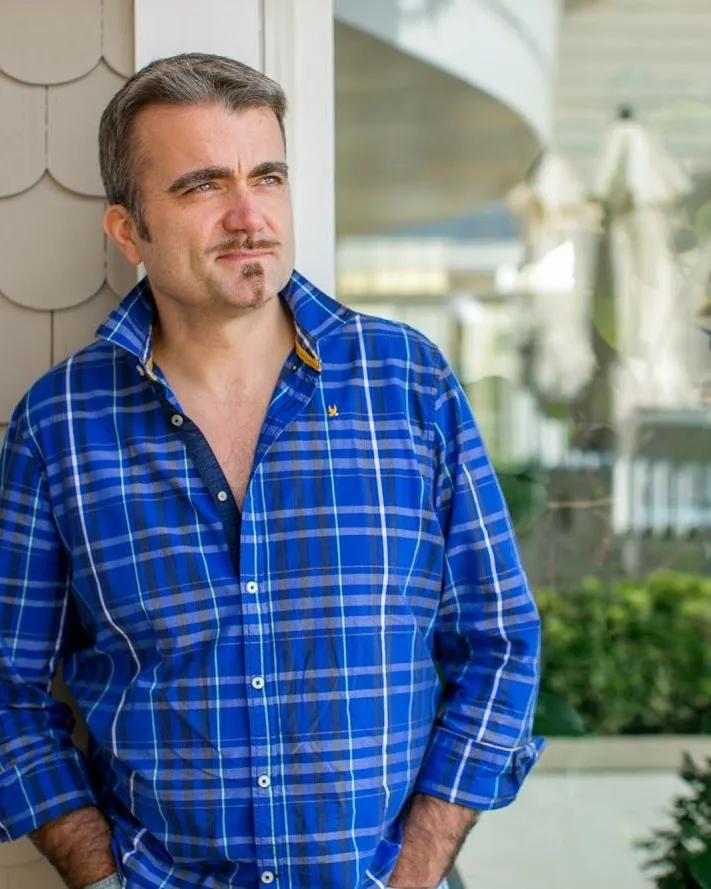 Olivier Collet adossé à une façade claire, les mains dans les poches